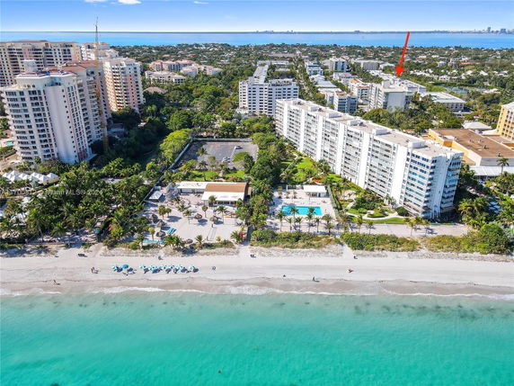 Aerial view of beachfront condominium buildings with a clear blue ocean and beach in the foreground.
