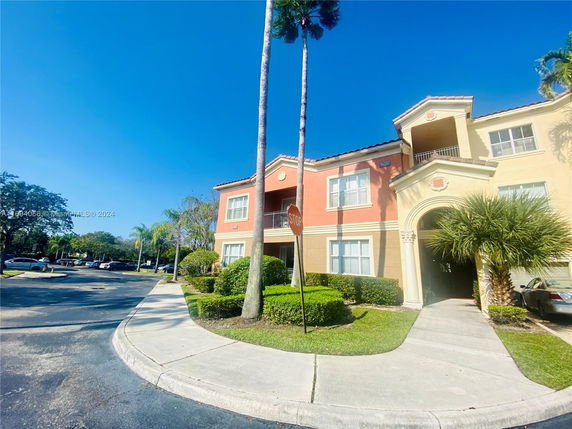 Front view of a two-story residential building with an arched entrance and pastel-colored facade.