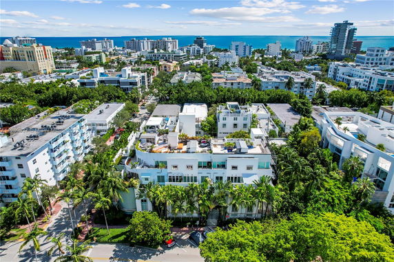 Aerial view of a cityscape with buildings and greenery near a coastline.