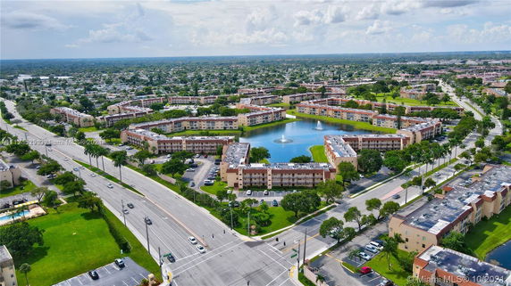 Aerial view of a residential area with multiple apartment buildings surrounding a pond with fountains.