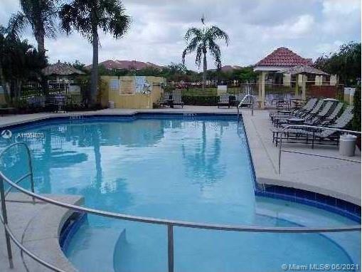 Outdoor swimming pool with lounge chairs and a gazebo.