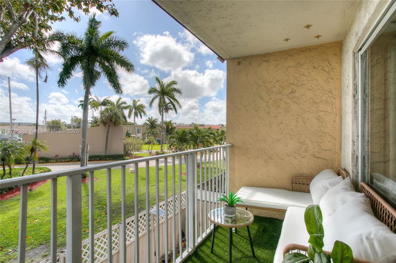 Balcony view overlooking palm trees and residential area.