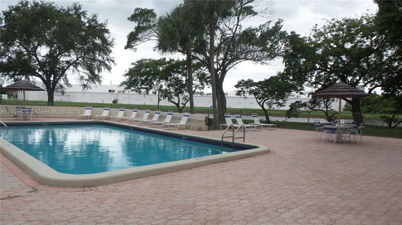 Outdoor swimming pool area with lounge chairs and umbrellas.