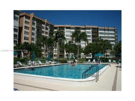 View of a multi-story condominium complex with a swimming pool in the foreground.