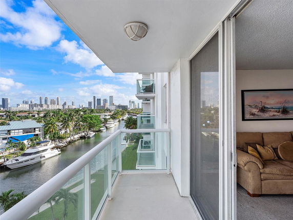 Balcony view of a waterfront area with boats and a city skyline in the distance.