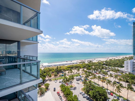 View from a high-rise balcony overlooking a beach and ocean.