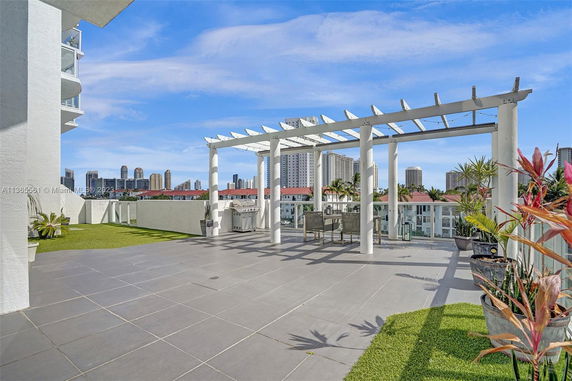 Rooftop area with pergola and seating, overlooking cityscape.