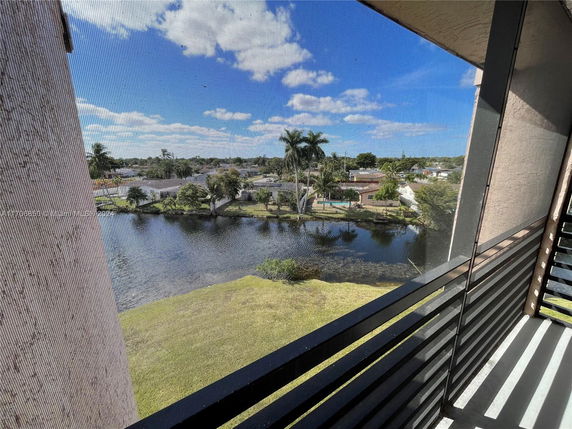 Panoramic view from a balcony showing a water body and surrounding houses.
