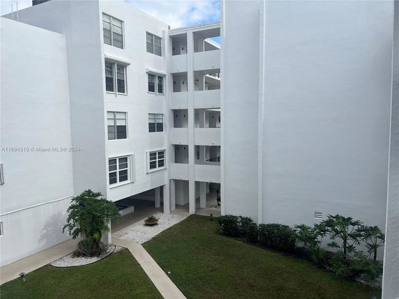 View of a multi-story white building complex with open corridors.