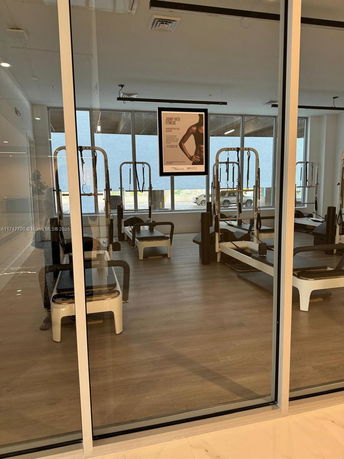 Interior view of a gym area with exercise equipment and large windows.