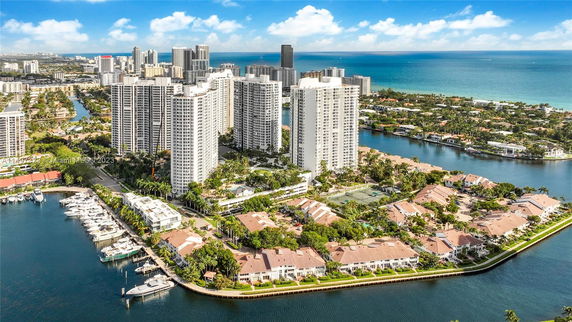 Aerial view of high-rise buildings near a waterfront with yachts.