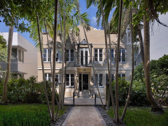 Front view of a two-story house with multiple windows and a shaded entrance.