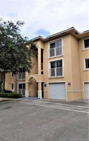 Front view of a three-story residential building with multiple balconies and garage doors.