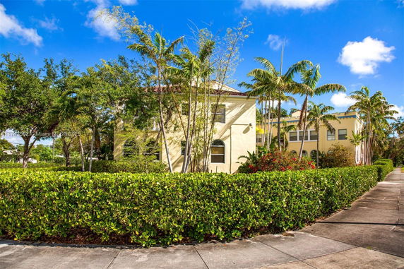 Front view of a two-story house with arched windows and surrounded by greenery.