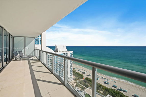 Panoramic view from a high-rise balcony overlooking the ocean and beach.