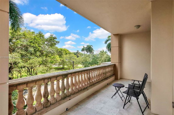 Balcony view with chairs overlooking a green landscape and trees.