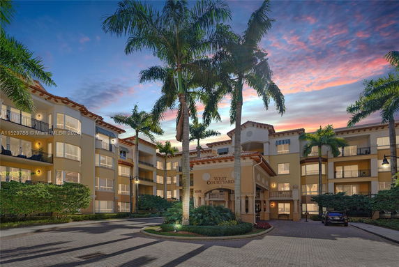 Front view of a multi-story residential building with palm trees.