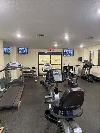 Indoor gym with exercise equipment including treadmills and stationary bikes.
