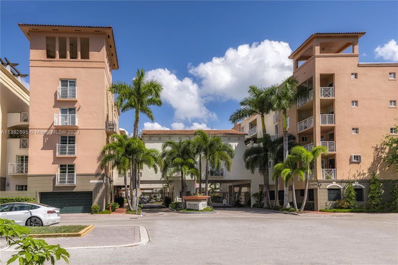 Front view of a multi-story residential complex with balconies and palm trees.