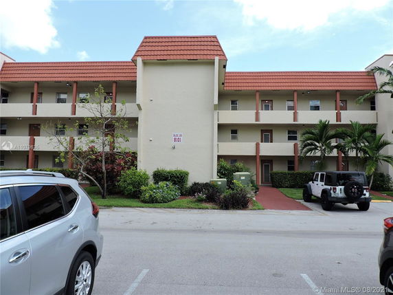 Front view of a three-story apartment building with a red tiled roof and balconies.