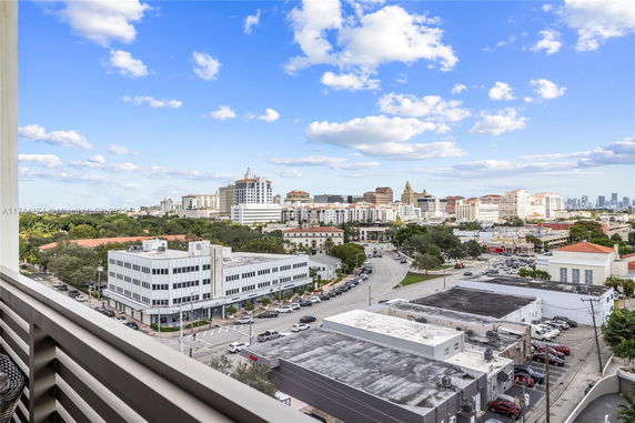 Panoramic cityscape view from a building, showing multiple buildings and a clear blue sky.
