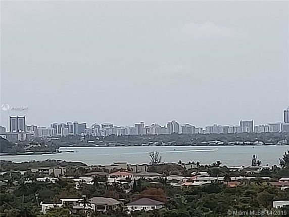 Wide angle view of city skyline over a body of water with residential area in the foreground.