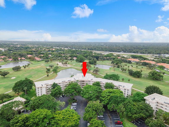 Aerial view of residential buildings surrounded by greenery and a golf course.