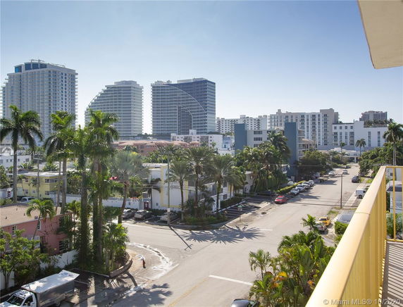 View from a balcony showing various buildings and palm trees in a urban area.