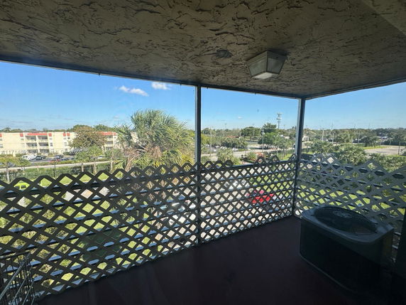 Panoramic view from a screened balcony showing a parking lot and nearby buildings.