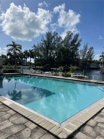 Outdoor swimming pool with surrounding seating area and view of trees.