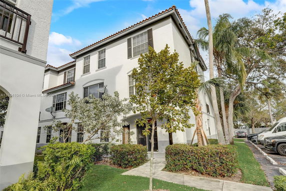 Front view of a three-story white residential building with balconies and a tile roof.