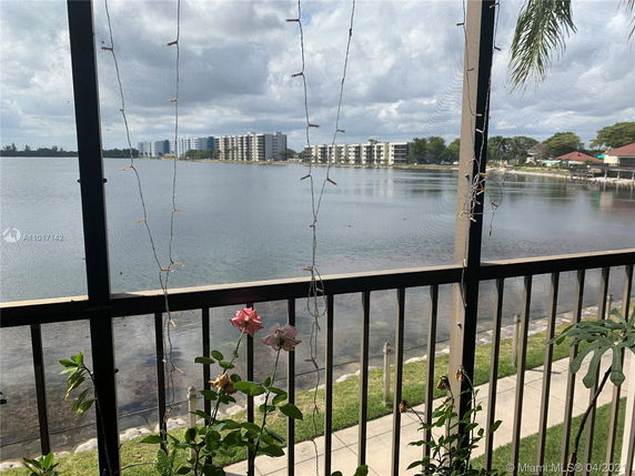 View from a balcony overlooking a lake with distant apartment buildings.