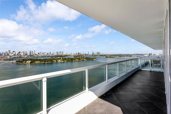 Panoramic view from a balcony overlooking water and a city skyline in the distance.