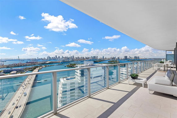 Panoramic view from a high-rise balcony overlooking city skyline and water.