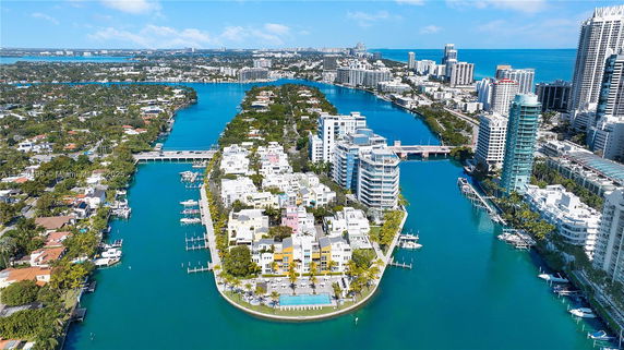 Aerial view of waterfront buildings surrounded by waterways and urban skyline.