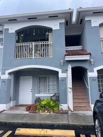 Front view of a two-story house with balconies and stairs.