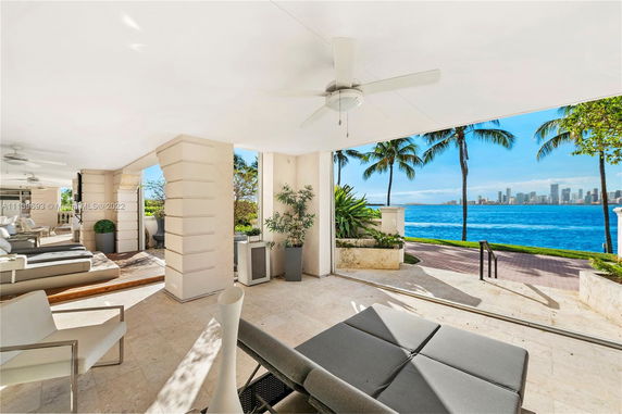 Covered outdoor patio area with lounge chairs and a view of water and city skyline.