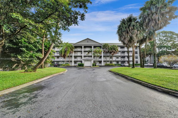 Front view of a multi-story residential building with balconies and a driveway.