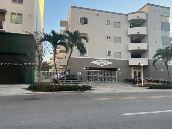 Front view of a multi-story apartment building with gated parking.