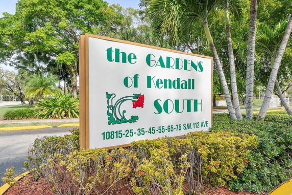 Sign for The Gardens of Kendall South with surrounding greenery.