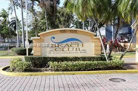 Sign for 'The Beach Club' at an outdoor location surrounded by palm trees.