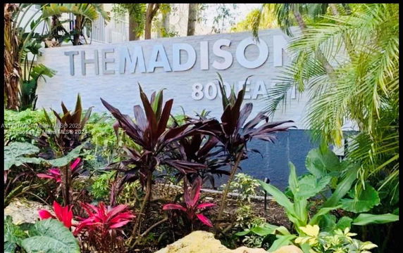Sign for The Madison surrounded by tropical plants.