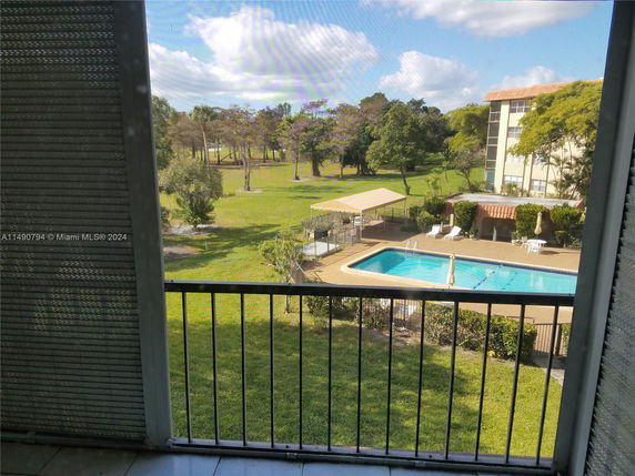 View from a building overlooking a swimming pool and green lawn area.