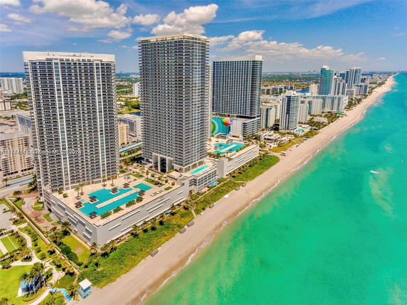 Aerial view of high-rise buildings along a beachfront with clear blue water.
