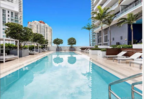 Outdoor swimming pool area with lounge chairs and surrounding buildings.