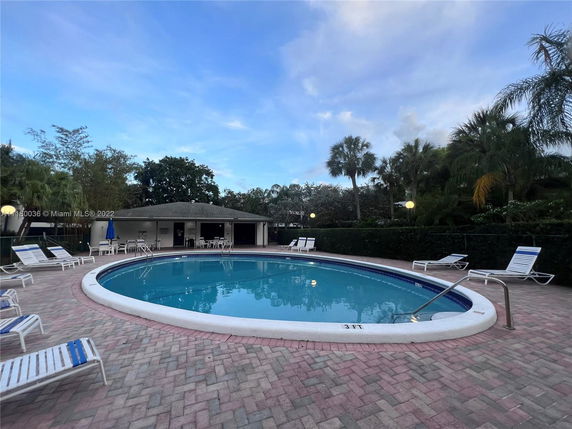 Outdoor swimming pool area with lounge chairs and surrounding trees.