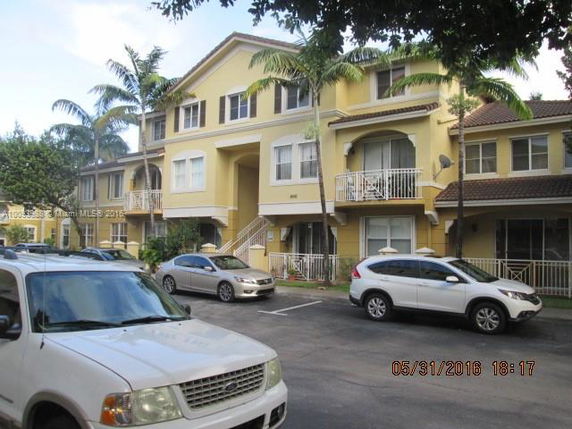 Front view of a multi-story residential building with parked cars in front.