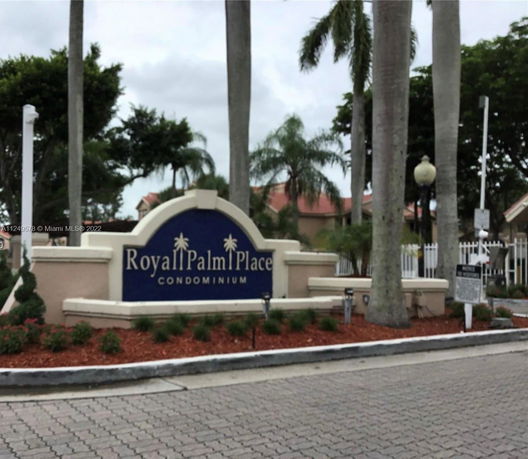 Entrance sign of Royal Palm Place condominium with surrounding palm trees.