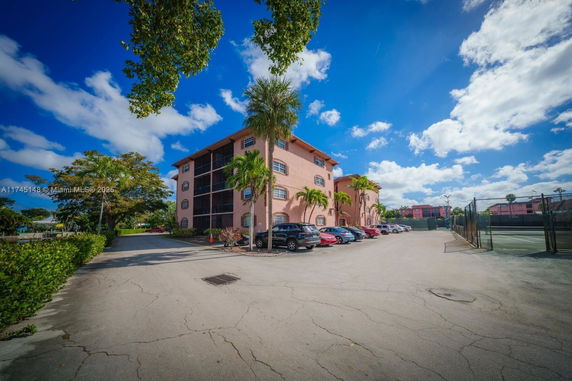 Front view of a multi-story residential building with adjacent parking area.