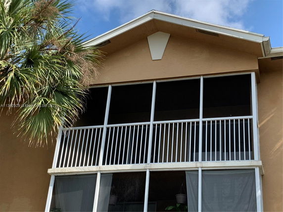 Front view of a house with screened balcony and sloped roof.